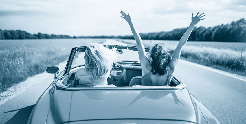 Blue Tone photo of 2 women driving a convertible on an open road.
